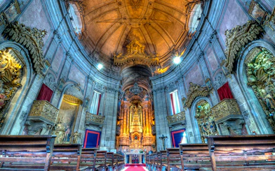 Clérigos Church interior with ornate altar and wooden pews, Porto, Portugal.