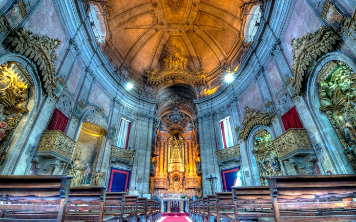 Clérigos Church interior with ornate altar and wooden pews, Porto, Portugal.