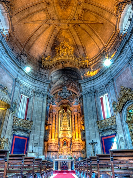 Clérigos Church interior with ornate altar and wooden pews, Porto, Portugal.