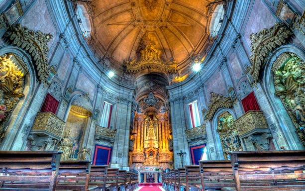Clérigos Church interior with ornate altar and wooden pews, Porto, Portugal.