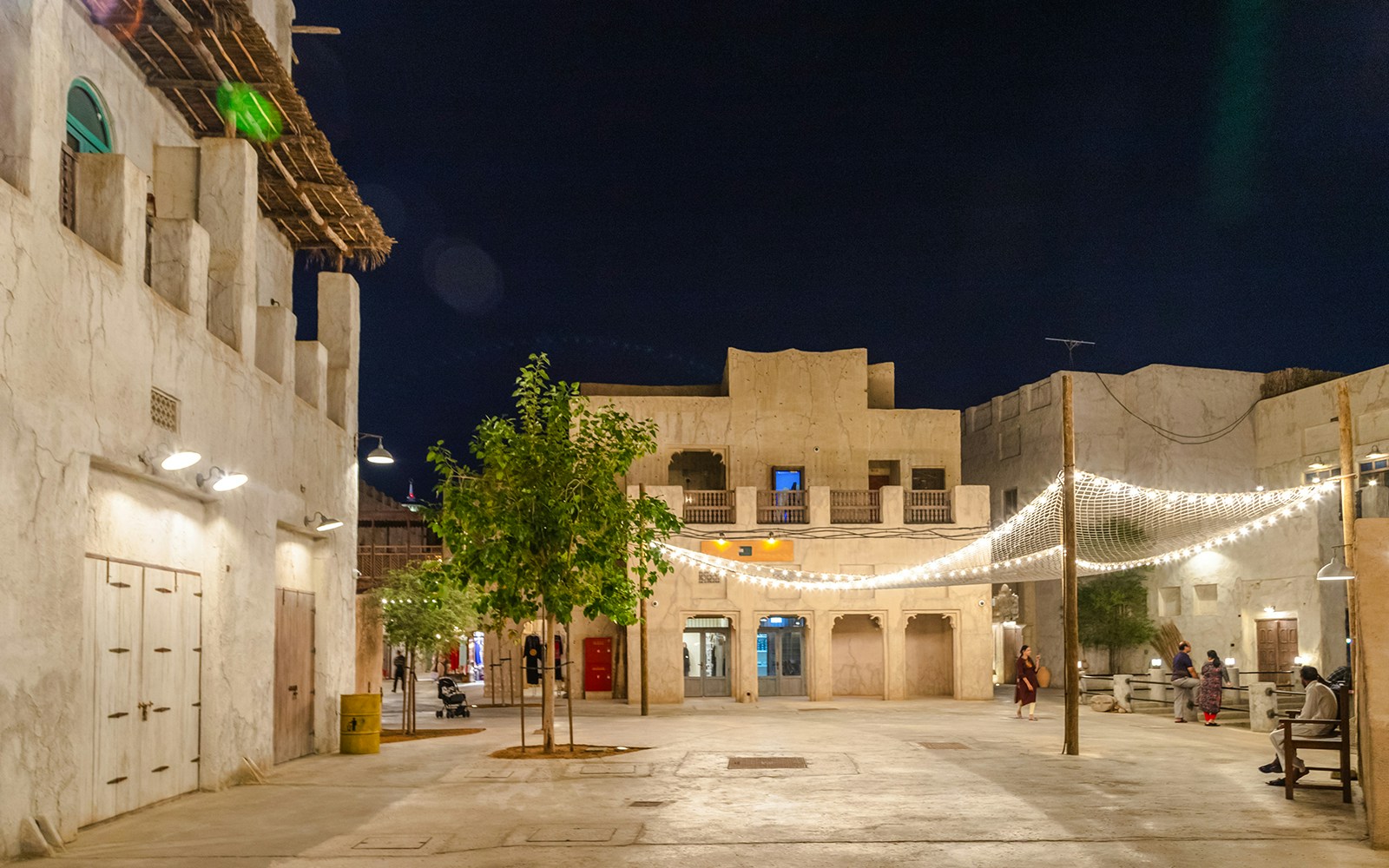 Historic courtyard in Al Fahidi District, Dubai, with traditional architecture and string lights at night.