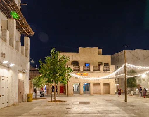 Historic courtyard in Al Fahidi District, Dubai, with traditional architecture and string lights at night.