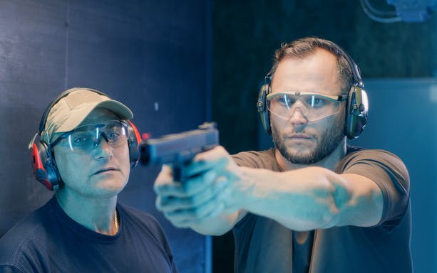 Instructor guiding man at shooting range in Warsaw.