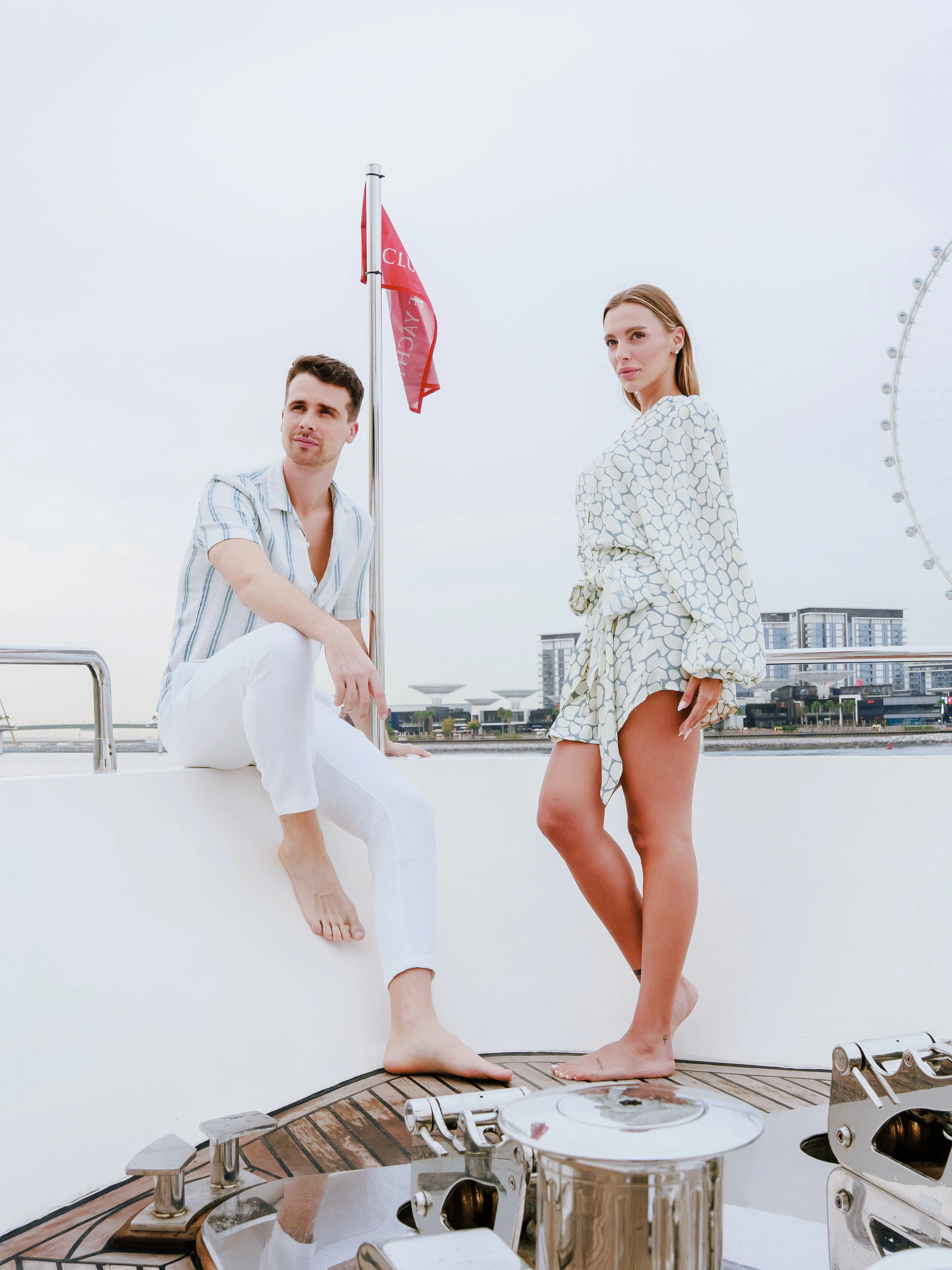 Couple on a luxury yacht with Dubai skyline and Ferris wheel in the background.