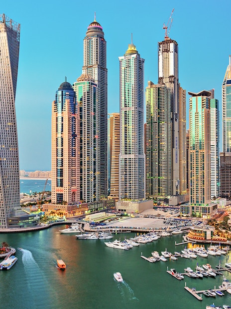 Aerial view of Dubai Marina with skyscrapers and yachts in the daytime.