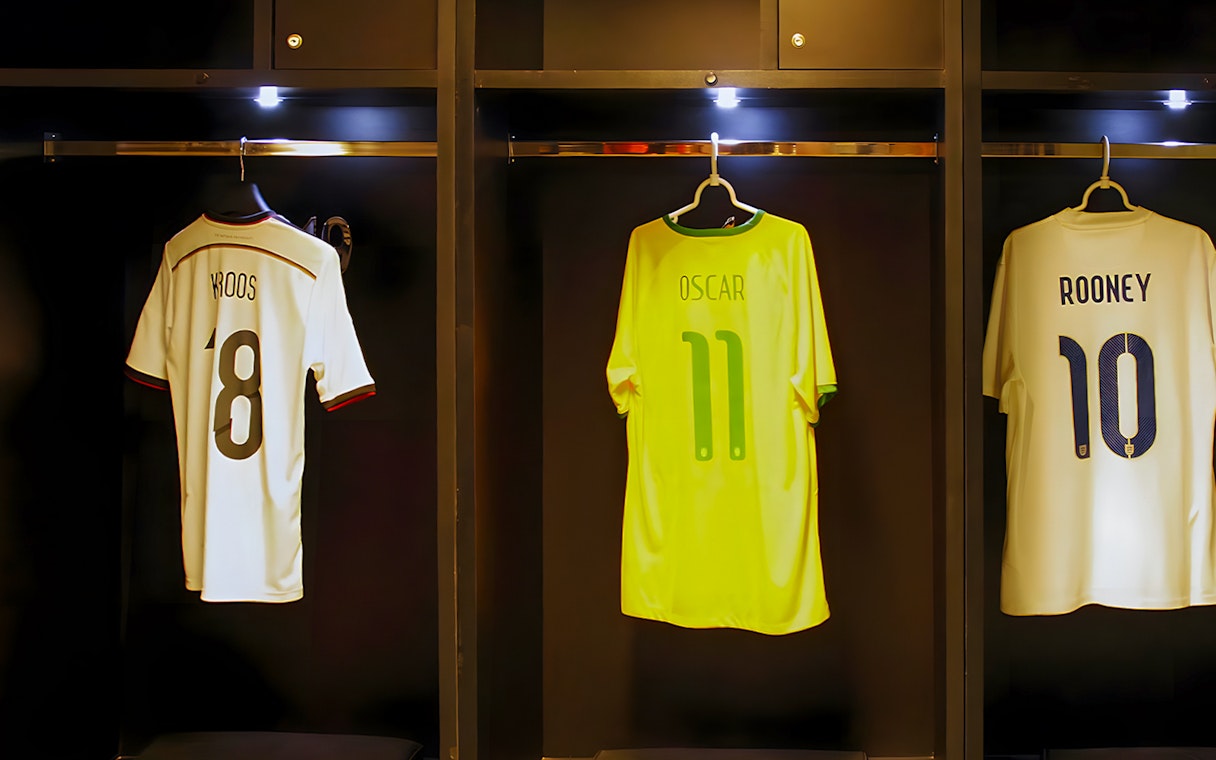 Jerseys of Kroos, Oscar, and Rooney hanging in a player dressing room.