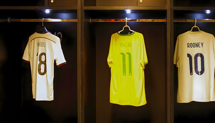 Jerseys of Kroos, Oscar, and Rooney hanging in a player dressing room.