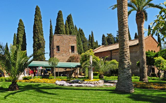 Catacombe di San Callisto garden with stone building and cypress trees in Rome.