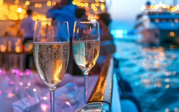 Champagne glasses on a Sydney New Year's Eve dinner cruise with festive lights.