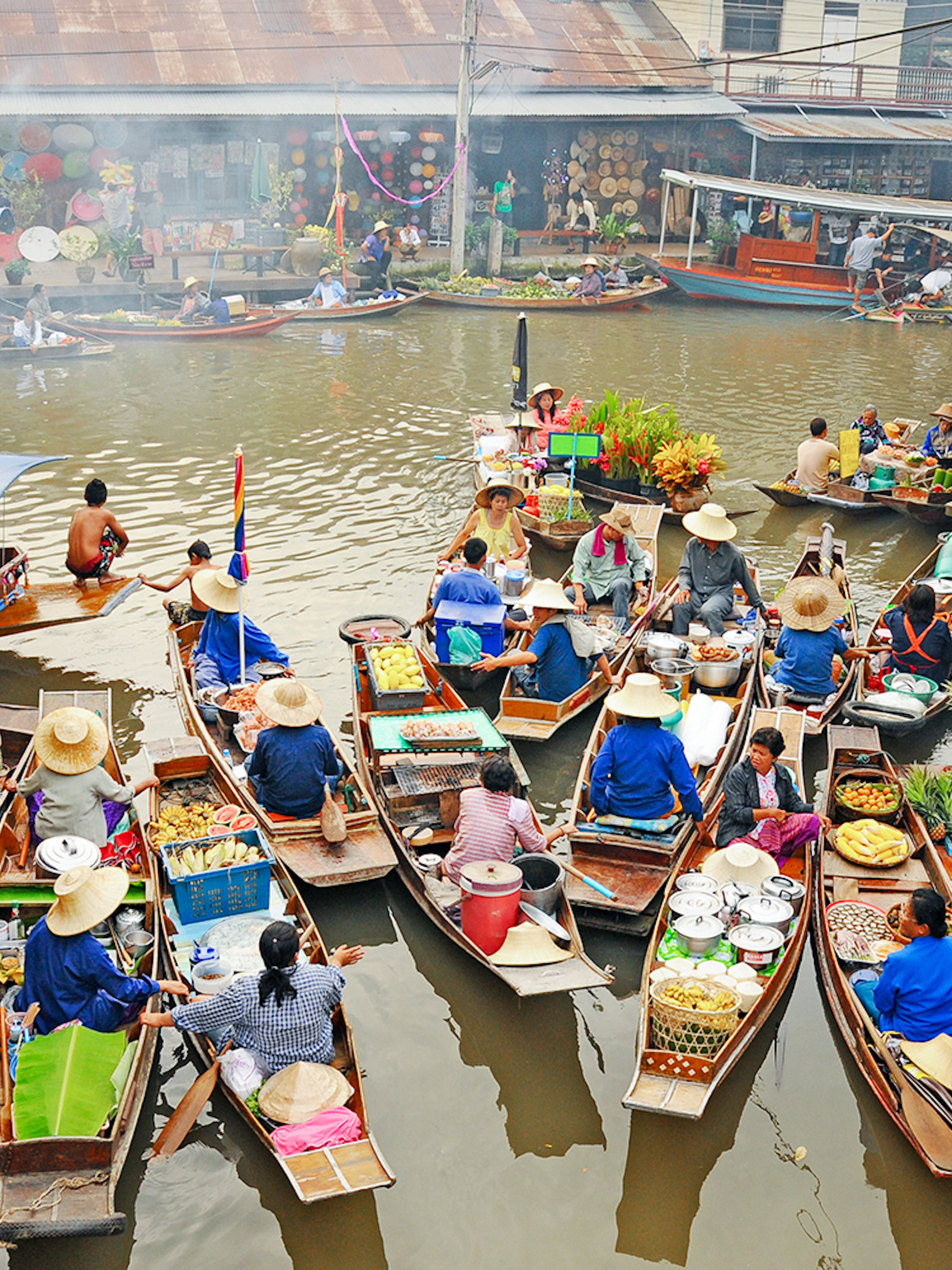 Boats with vendors selling goods at Amphawa Floating Market, Thailand.