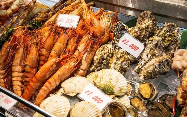Seafood display at Osaka market featuring prawns, oysters, and scallops, highlighting local street food culture.