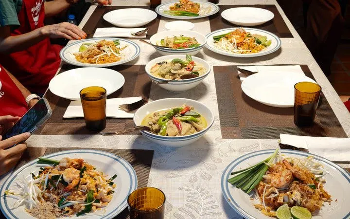 Thai dishes on a table during a cooking class with market visit and boat ride at a historic garden house.