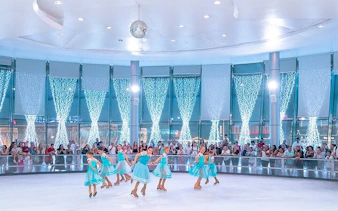 Ice skaters performing at Soho Square Ice Rink, Sharm El Sheikh, with an audience watching.