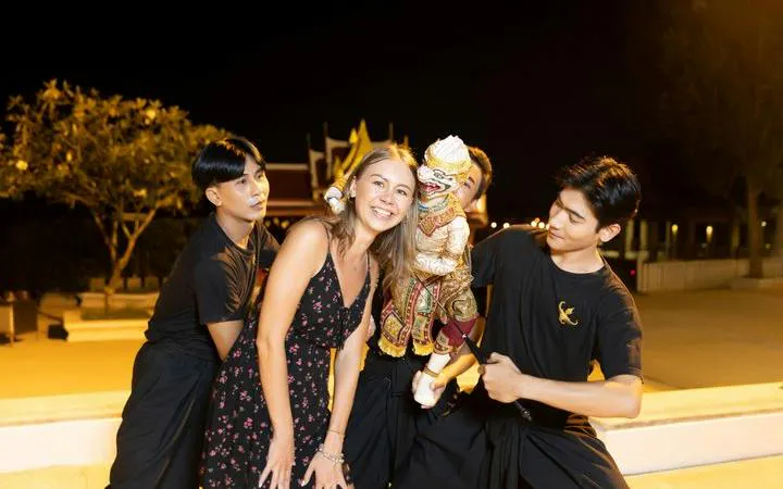 Siam Niramit performers with a guest and traditional puppet in Phuket.