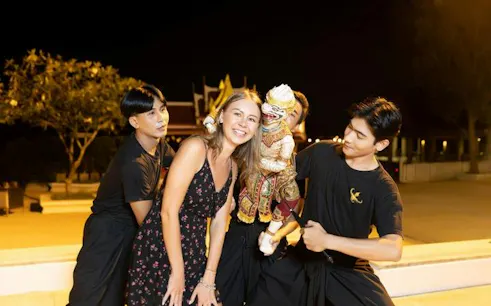 Siam Niramit performers with a guest and traditional puppet in Phuket.