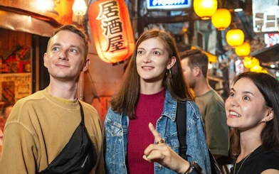 Shinjuku bar hopping tour group exploring vibrant alley with lanterns in Tokyo.