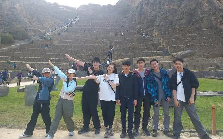 Group of tourists at Ollantaytambo ruins, Sacred Valley, with terraced stone steps in the background.