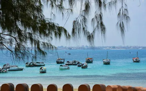 Boats anchored in the turquoise waters of Stone Town, Zanzibar, with distant shoreline.