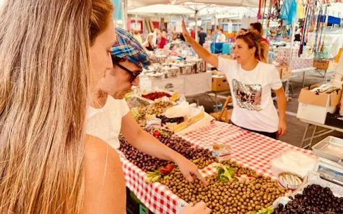 Visitors selecting olives at a Palermo market for a rooftop cooking class.