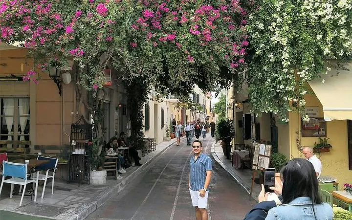 Street in Athens with tourists under vibrant bougainvillea, part of Instagram Photo Walking Tour.