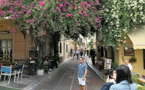 Street in Athens with tourists under vibrant bougainvillea, part of Instagram Photo Walking Tour.