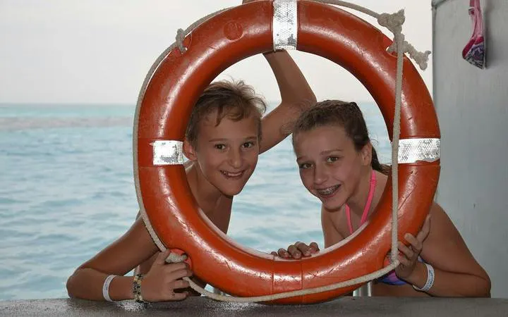 Children smiling through a life ring on a boat during a Hurghada sea trip.