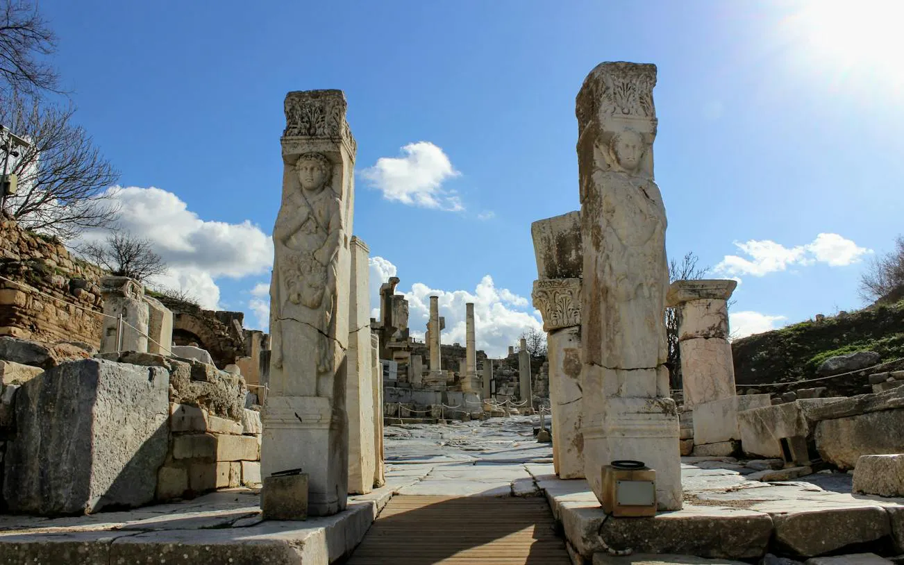Ancient stone columns and ruins on Curetes Street, Ephesus, under a clear blue sky.