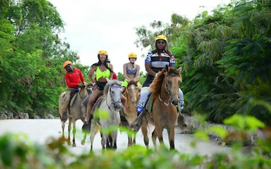 Horseback riders on a trail surrounded by lush greenery in Punta Cana.