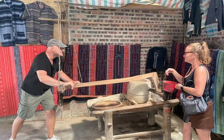 Man and woman engaging in traditional rice milling during Sapa guided trek experience.