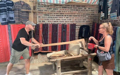 Man and woman engaging in traditional rice milling during Sapa guided trek experience.