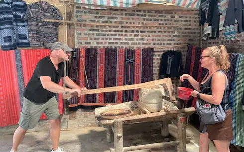 Man and woman engaging in traditional rice milling during Sapa guided trek experience.