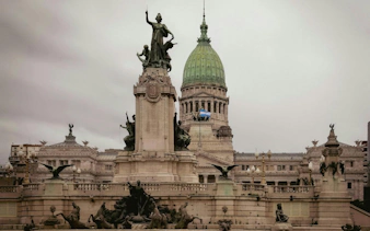 Monument at Plaza de Mayo with Argentine flag and National Congress building, Buenos Aires.