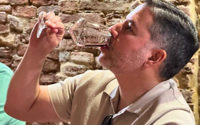 Man tasting wine in a rustic setting during a private tour in Siena, Italy.