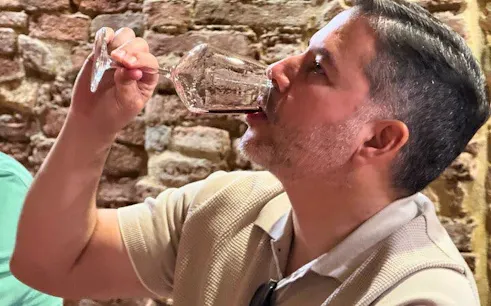 Man tasting wine in a rustic setting during a private tour in Siena, Italy.