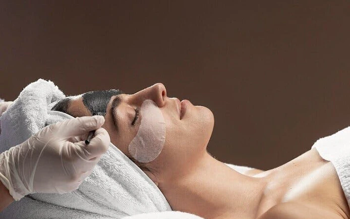 Person receiving facial treatment during Moroccan Hammam ritual in Marrakesh bathhouse.