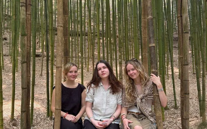 Three people sitting in a bamboo forest during Mu Cang Chai motorbike tour.