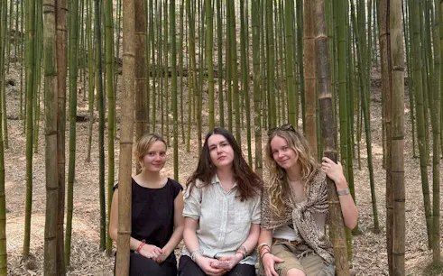 Three people sitting in a bamboo forest during Mu Cang Chai motorbike tour.