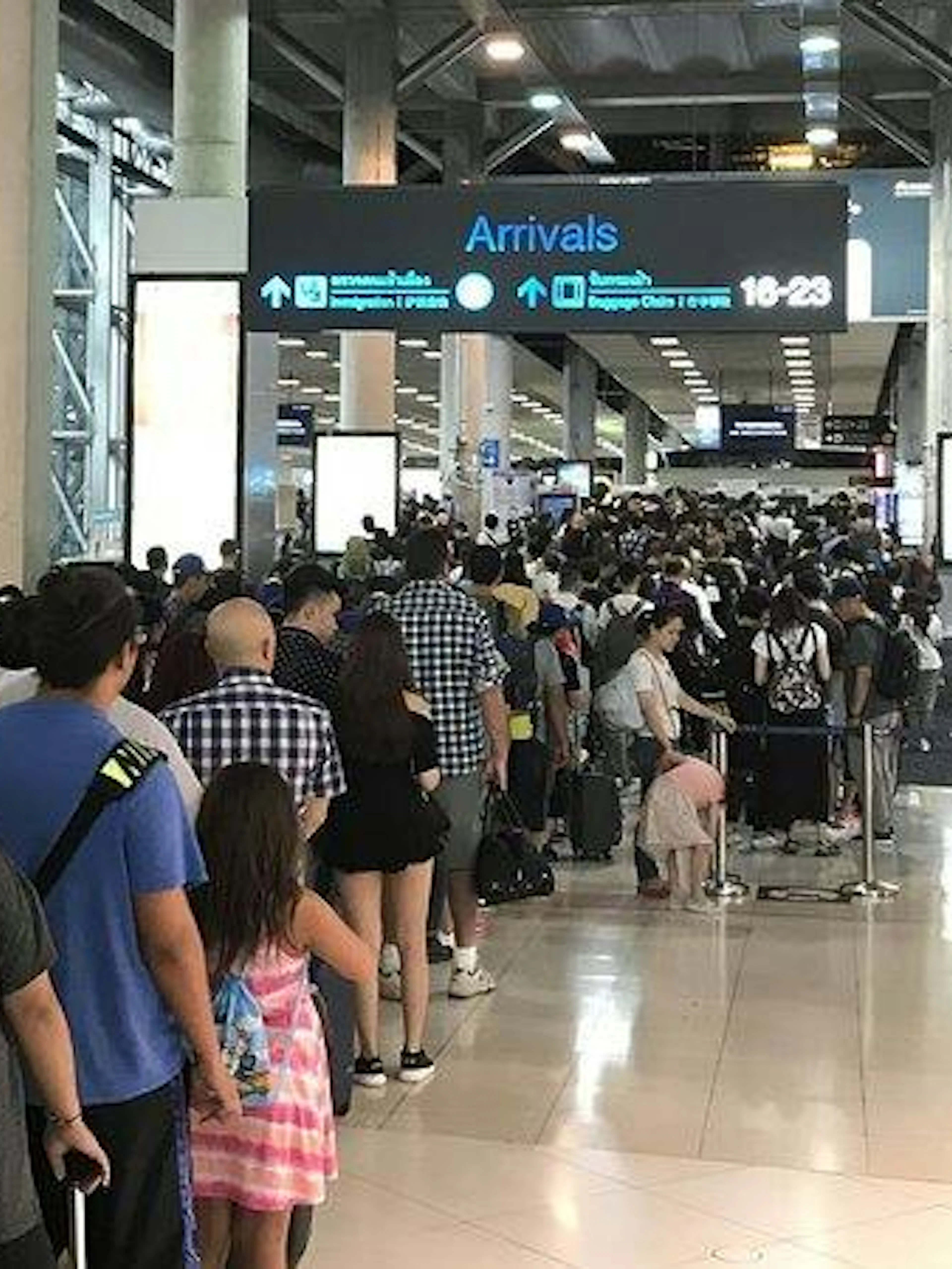 Phuket Airport arrivals area with long queue for immigration services.