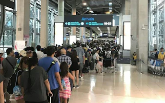 Phuket Airport arrivals area with long queue for immigration services.