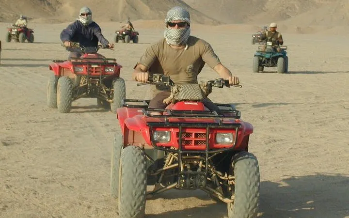 Quad biking adventure in Sharm El Sheikh desert with group riding across sandy terrain.