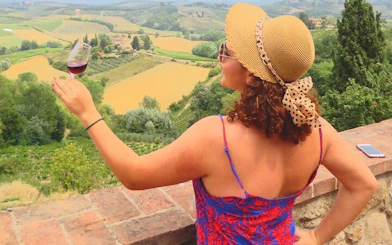 Woman enjoying wine overlooking Tuscany vineyards on Rome to Siena day trip.