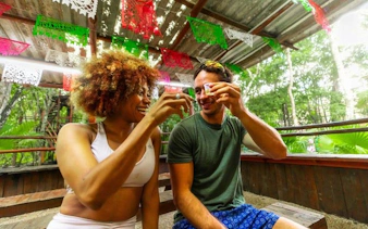 Couple enjoying tequila tasting under colorful banners in a cenote setting.