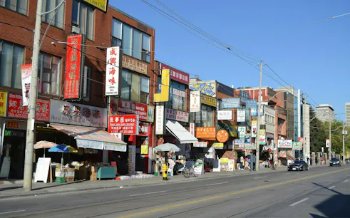 Shops and signs in Toronto's Chinatown along Spadina Avenue, part of a self-guided audio walk.