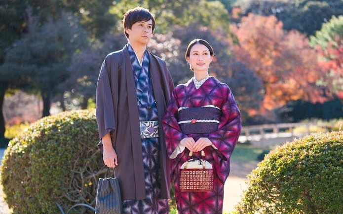 Couple in silk kimonos at Shinjuku Gyoen National Garden, Tokyo, with autumn foliage.