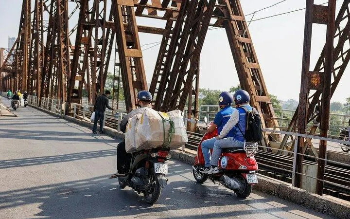 Vespas crossing Long Bien Bridge in Hanoi during countryside tour to Bat Trang Ceramic Village.