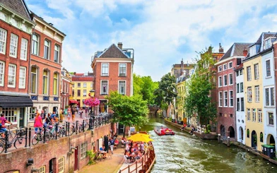 Utrecht canal with historic buildings and people enjoying a riverside cafe, part of a self-guided walking tour.