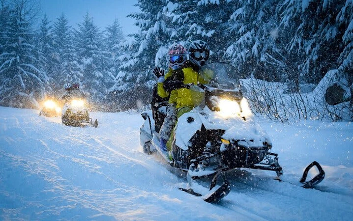 Snowmobiles driving through snowy forest in Zakopane during guided adventure tour.