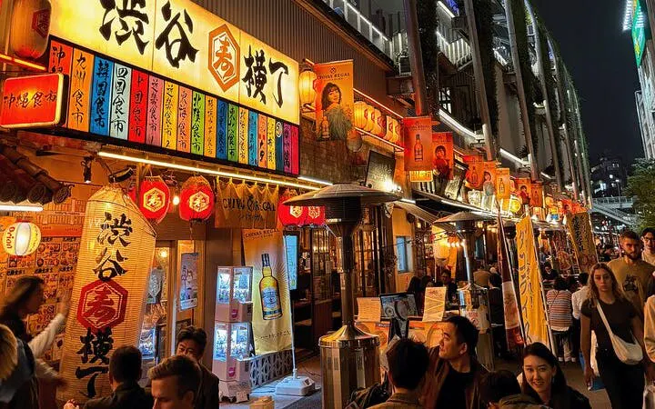 Shibuya street with vibrant signs and bustling crowd during Tokyo walking tour.