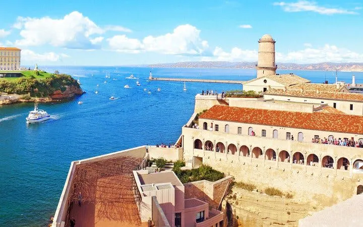 Marseille harbor view with Fort Saint-Jean and boats, part of self-guided walking tour.