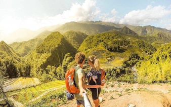 Couple trekking with backpacks overlooking rice terraces in Sapa, Vietnam.